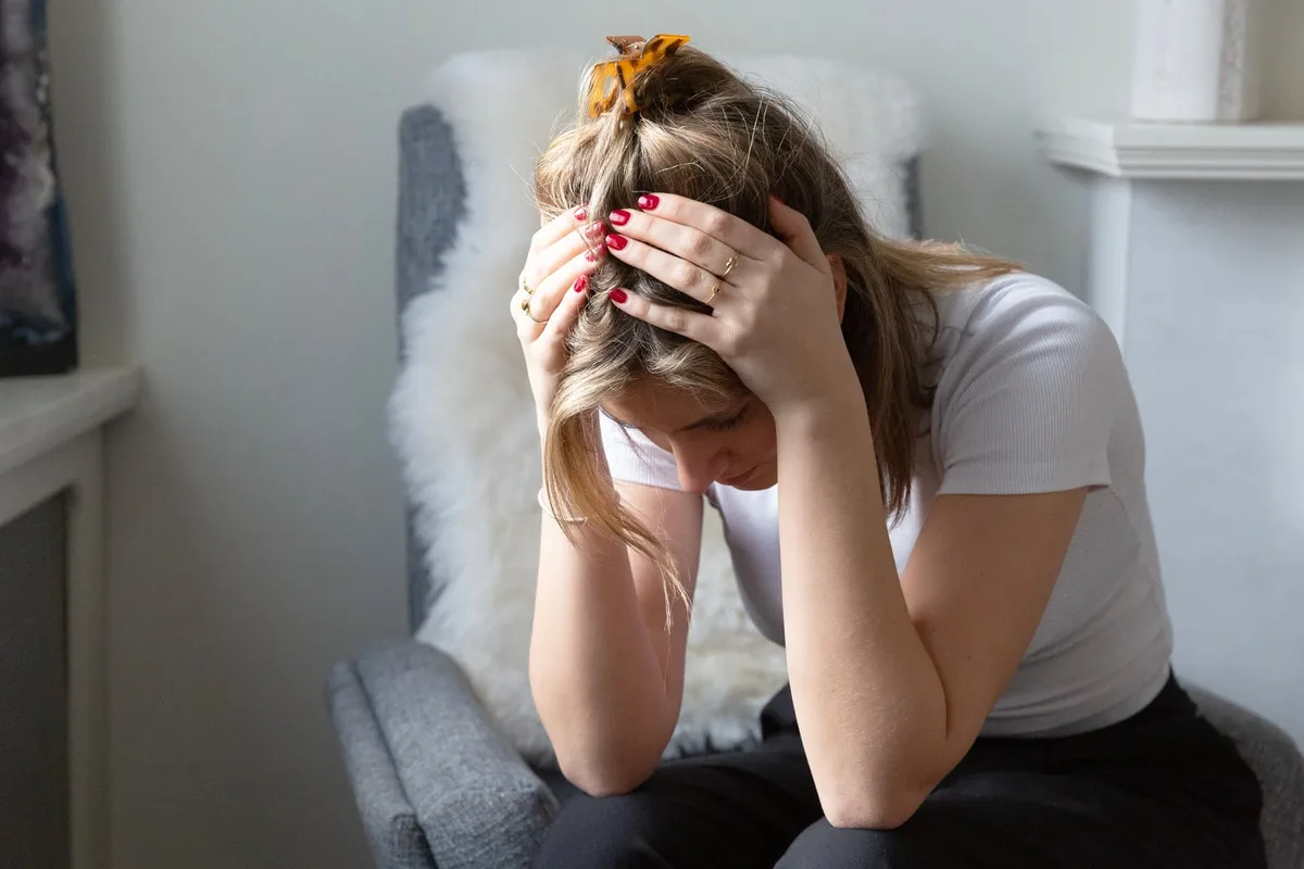Vrouw met haar hoofd in haar handen van frustratie door rugpijn