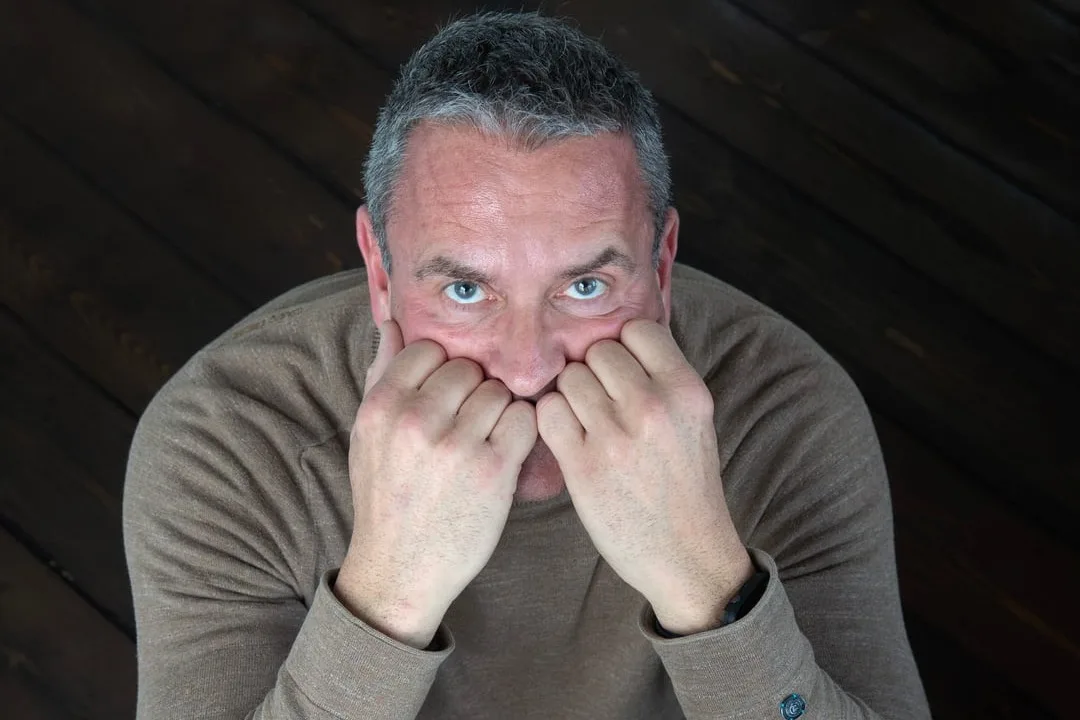 Man zit met zijn hoofd in zijn handen en kijkt omhoog