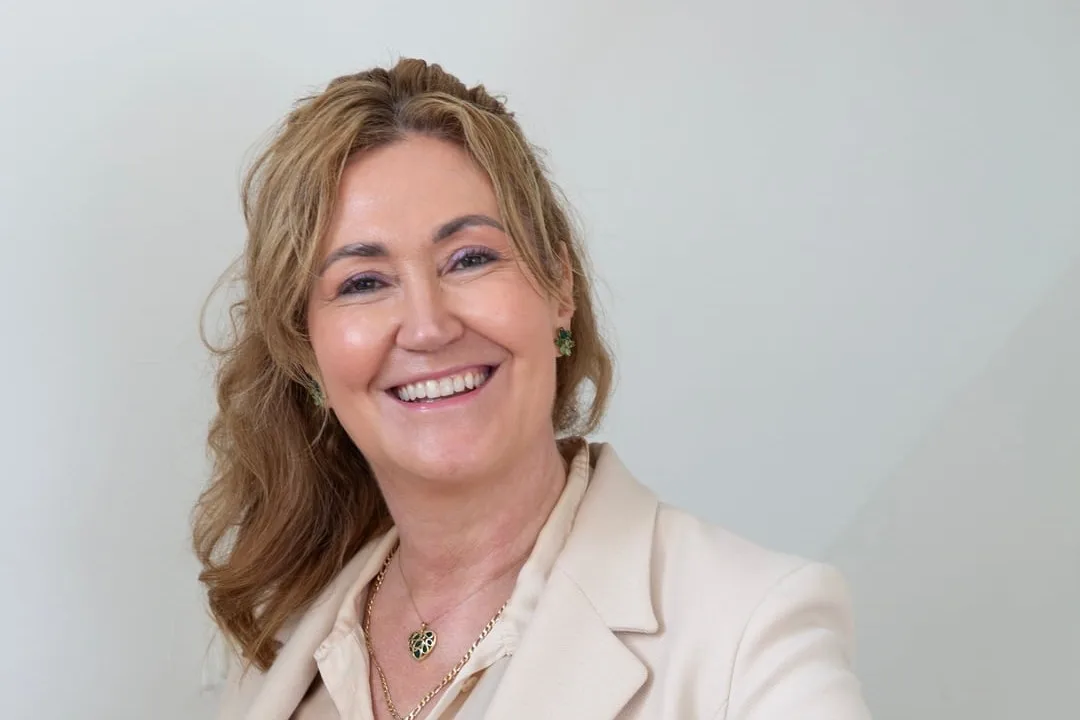 Ilse Bink staat lachend bij de trap in haar praktijk